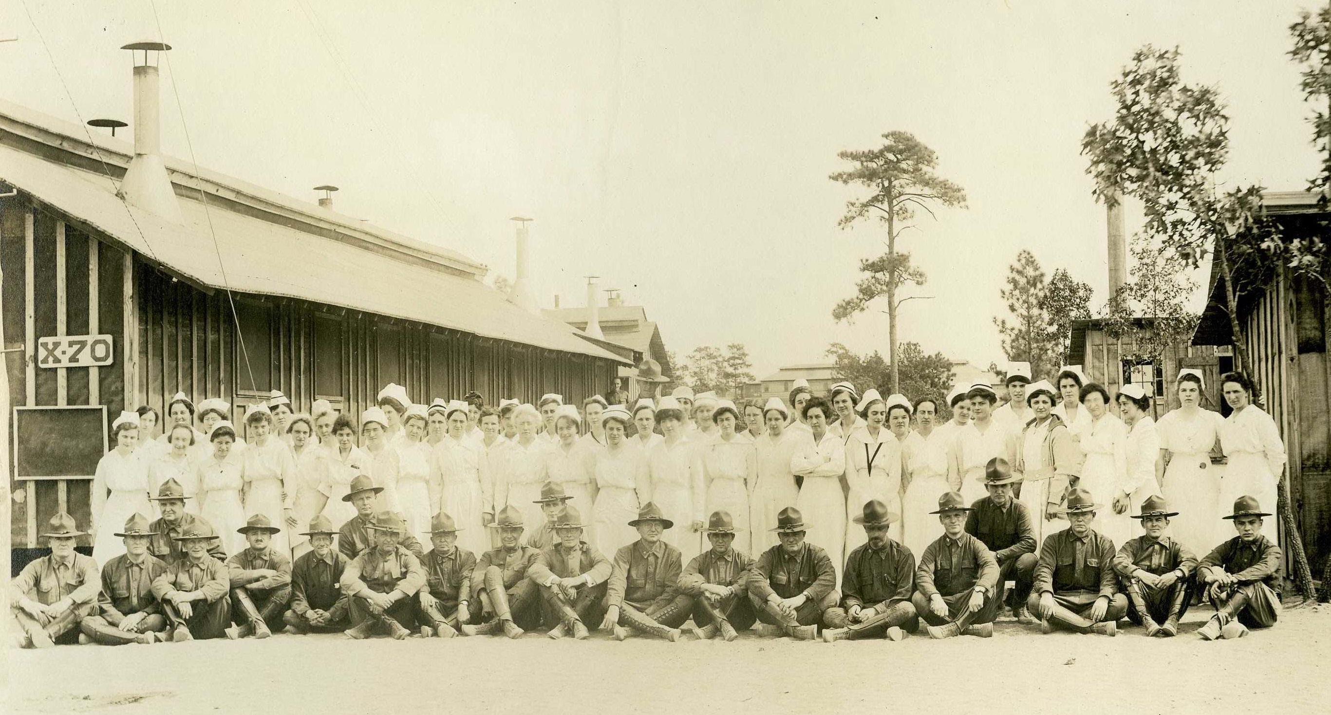 Females nurses standing in back row, male medical officers seated in front row, outside at Camp Jackson Base Hospital.