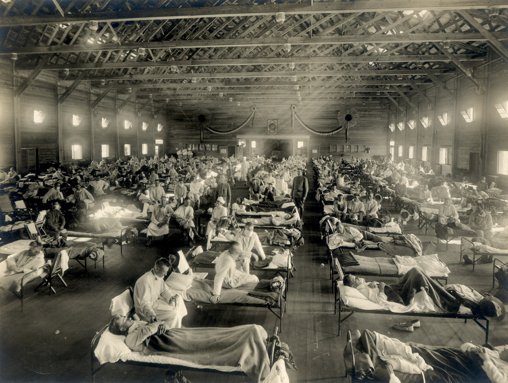 Rows of cots with influenza patients cover the floor of emergency hospital.