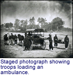 Staged photograph showing troops loading an ambulance.